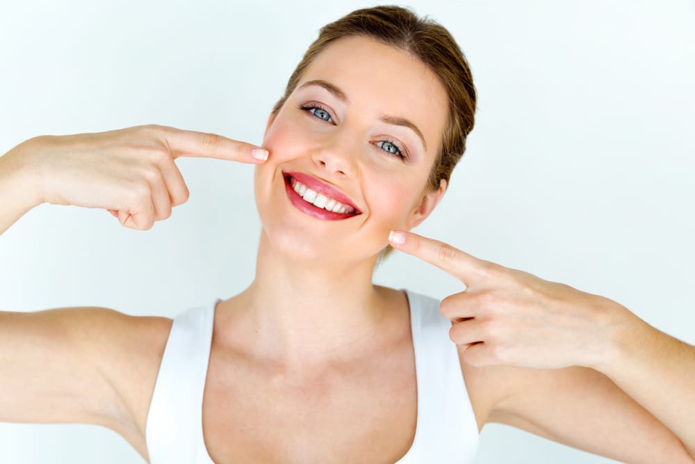 Women pointing at her mouth showing off her white teeth